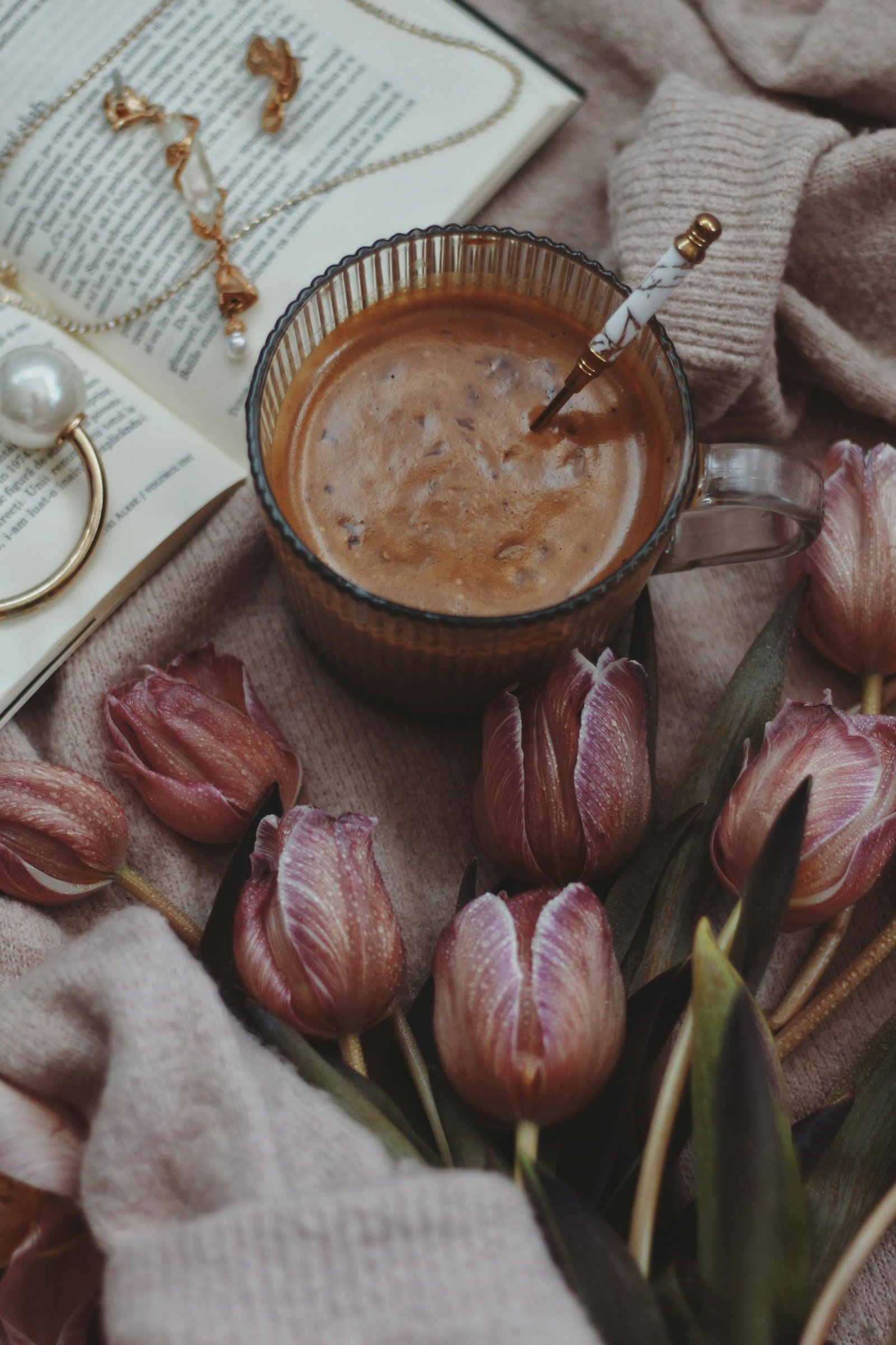 A warm and cozy composition featuring a coffee, tulips, and an open book for a relaxing vibe.